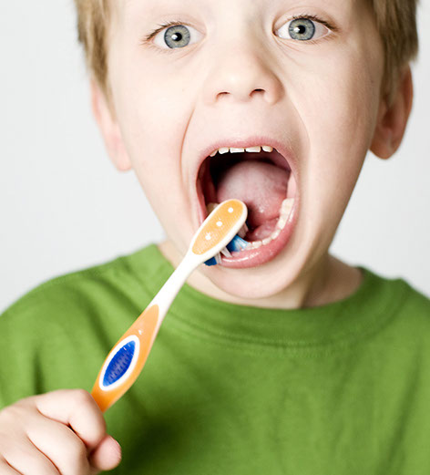 Little boy excitedly brushing his teeth.  VERY selective focus on eyes for dramatic effect.  Very shallow depth of field for dramatic/artistic purposes.