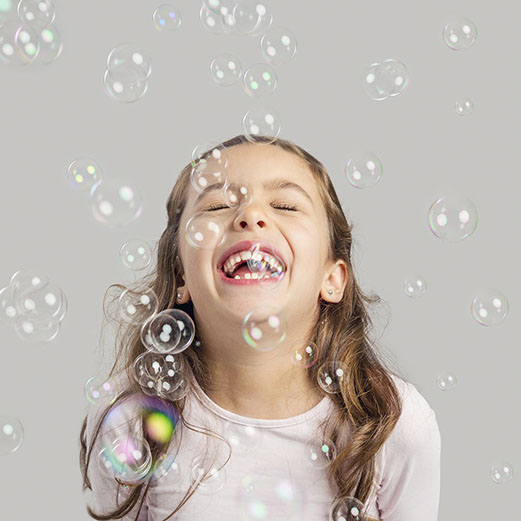 Cute little girl playing with soap bubbles